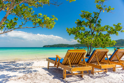 Chairs on beach against blue sky