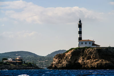 Low angle view of lighthouse on rock formations against sky