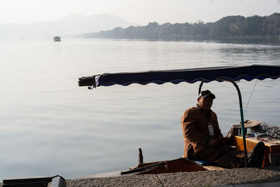 Man sitting on boat against lake