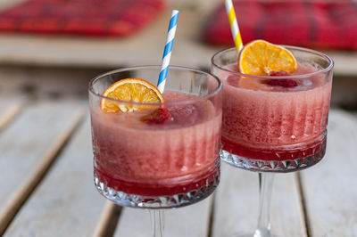 Close-up of two red cocktails in vintage glasses on white pallet table in bar