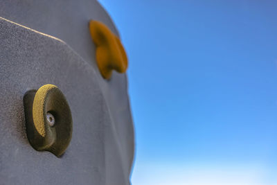 Low angle view of yellow wheel against clear blue sky