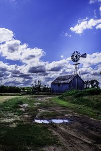 Wind turbines on landscape against cloudy sky