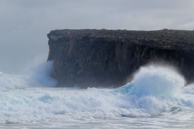 Waves splashing on rock formation in sea