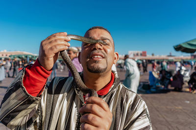 Portrait of man holding camera against sky