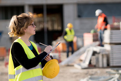 Side view of female architect working at construction site