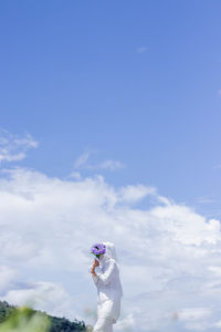Woman standing on white umbrella against sky
