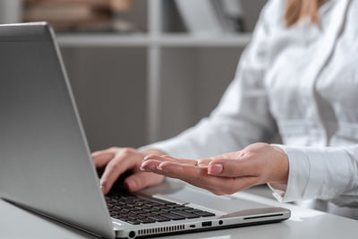 Midsection of woman using laptop on table