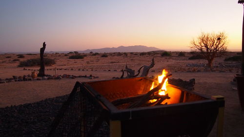 Bonfire on desert against clear sky during sunset