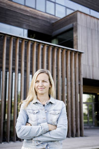 Woman with arms crossed standing against building