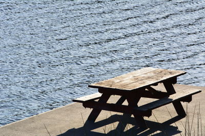 High angle view of wooden bench on pier at lake