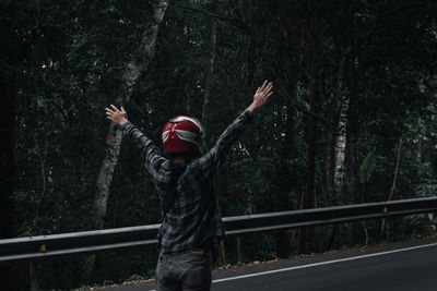 Rear view of man standing by railing in forest