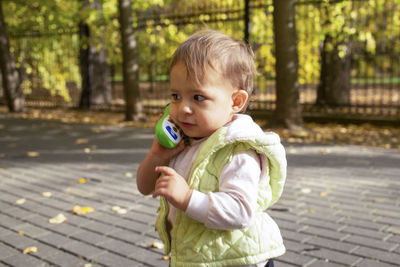 Cute girl talking on toy mobile phone outdoors