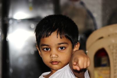 Portrait of cute boy pointing at home 