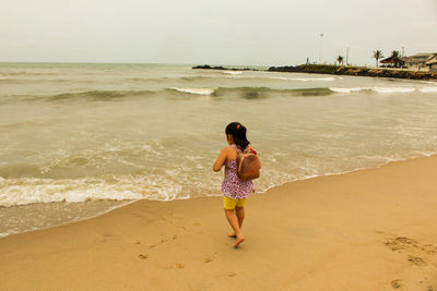 Rear view of girl walking at beach