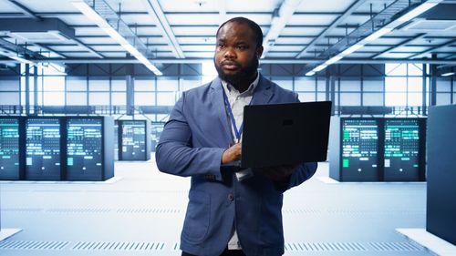 Young man using laptop while standing in office