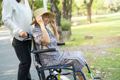 Side view of woman using mobile phone while sitting on field