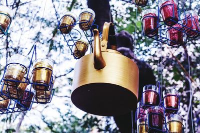 Low angle view of artwork made from teapot and glasses hanging to tree