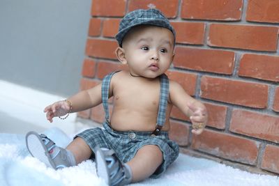 Cute baby girl sitting on brick wall