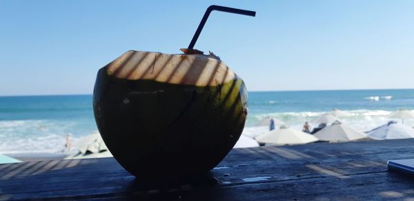 Close-up of drink on table at beach against clear sky