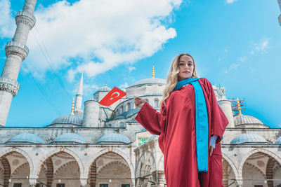 Low angle view of girl standing against mosque