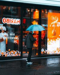 Rear view of woman standing on wet street in rain