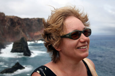 Middle-aged woman enjoying wind on the sea coast. woman is wearing sunglesses. mental health concept