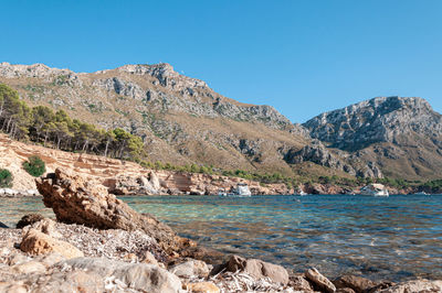 Scenic view of sea and mountains against clear blue sky