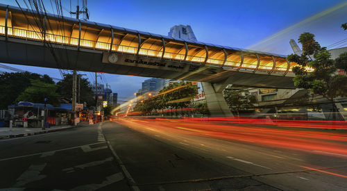 Light trails on bridge over road against sky in city