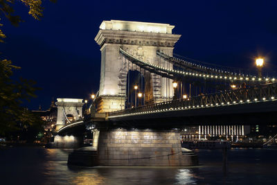 Illuminated bridge over river at night