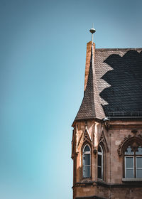 Low angle view of cross and building against clear blue sky