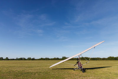 Powered hang glider on field against sky