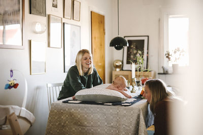 Smiling mothers relaxing at home with newborn baby