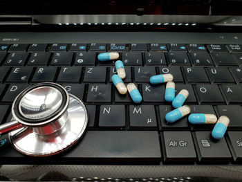 High angle view of stethoscope with medicine examining computer keyboard