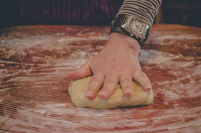 Close-up of hand kneading dough on counter