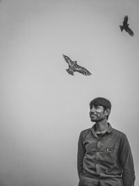 Young man looking at bird flying against wall