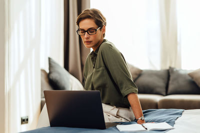 Beautiful woman using laptop sitting at home