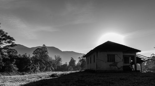 House on field by trees against sky