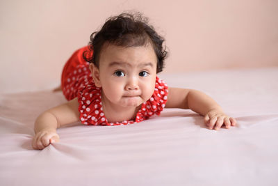 Portrait of cute baby girl lying on bed at home