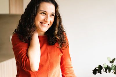 Portrait of young woman standing against wall