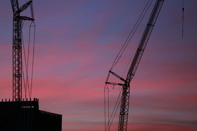 Low angle view of silhouette electricity pylon against romantic sky