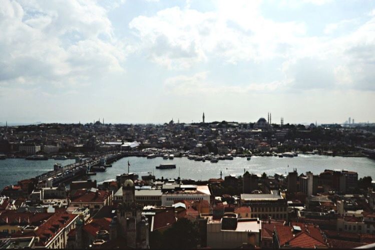 HIGH ANGLE VIEW OF CITYSCAPE AGAINST SEA