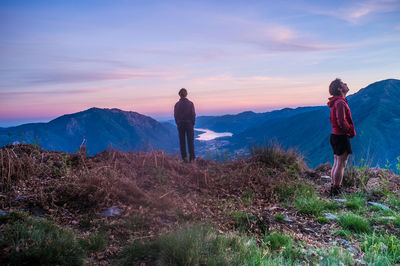 Rear view of man standing on mountain against sky during sunset