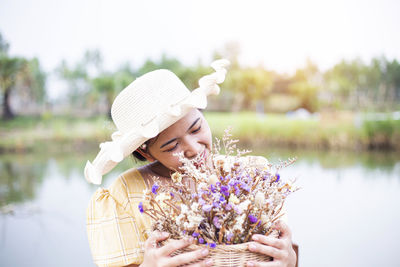 Close-up of woman holding flowers while sitting against lake