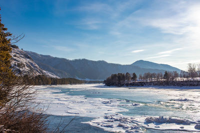 Scenic view of lake by snowcapped mountains against sky