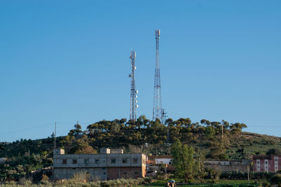 Low angle view of communications tower against clear blue sky