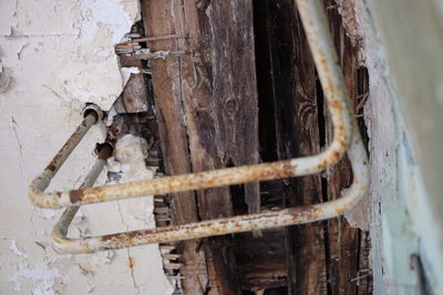 Close-up of rusty pipes at wooden wall in abandoned house