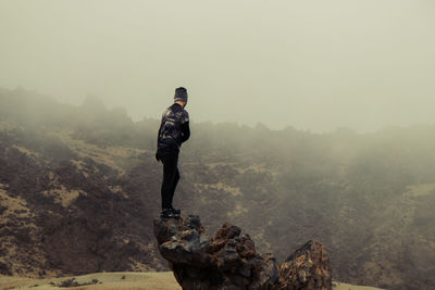 Man standing on rock looking at mountains