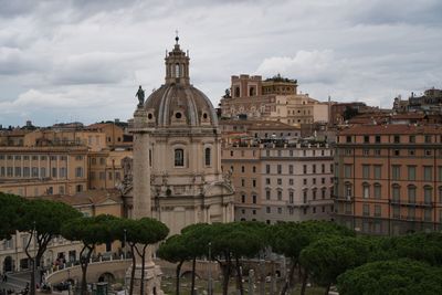 Buildings in city against cloudy sky