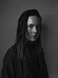 Portrait of beautiful young woman standing against wall