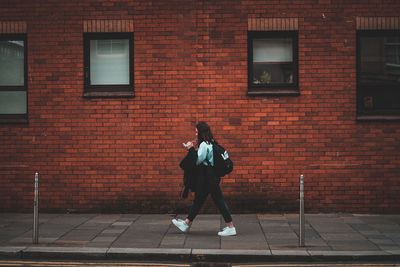 Full length of man standing against brick wall